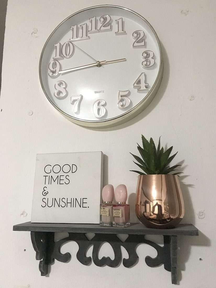Wall clock above a shelf with a planter